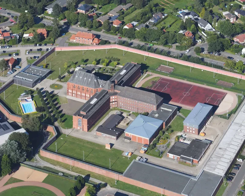 Blick aus der Luft aus einen kreuzförmigen Gefängnisbau mit einer Anstaltskirche.