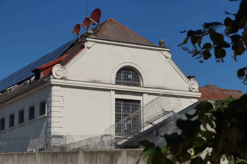 Ein Renaissancegebäude mit vergitterten Fenstern hinter einer Mauer mit Stacheldraht.