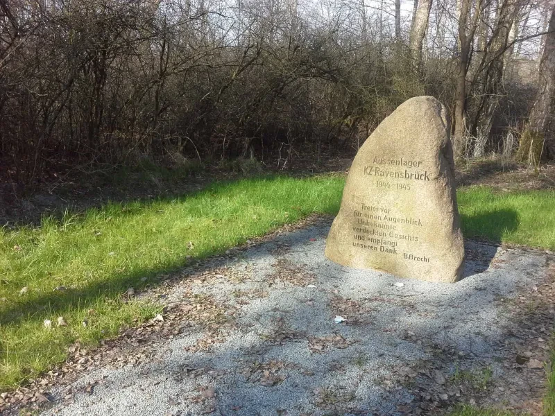 Ein Gedenkstein mit der Inschrift „Aussenlager KZ-Ravensbrück / 1944–1945 / Tretet vor / für einen Augenblick / Unbekannte / verdeckten Gesichts / und empfangt / unseren Dank / B. Brecht“