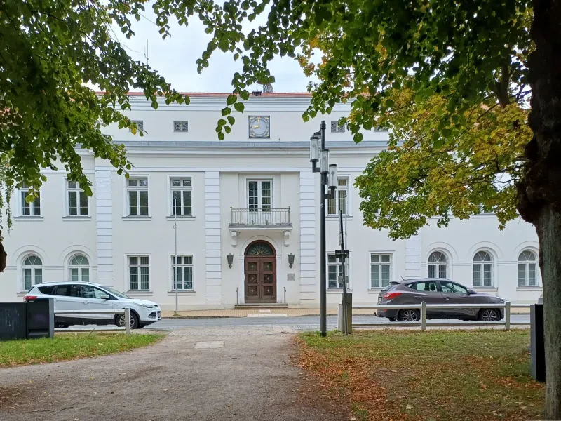 Das Salongebäude in Bad Doberan, 2025, Außenansicht. Ein weißes zweistöckiges Gebäude, davor eine Straße mit parkenden Autos.
