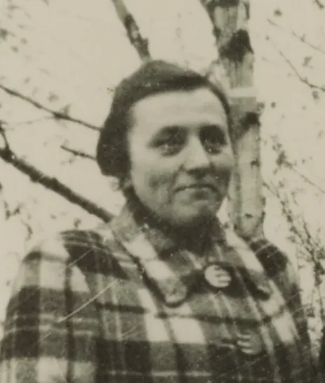 Eine Frau im Mantel, dahinter ein kahler Baum.