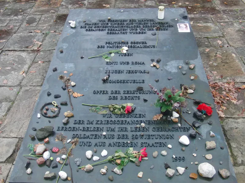 Gedenktafel mit dem Text: „Wir gedenken der Männer, Frauen und Kinder aus vielen Ländern, die im Konzentrationslager Bergen-Belsen gefangen gehalten und um ihr Leben gebracht wurden[:] Politische Gegner des Nationalsozialismus[,] Juden[,] Sinti und Roma[,] Zeugen Jehovas[,] Homosexuelle[,] Opfer der Zerstörung des rechts[.] Wir gedenken der im Kriegsgefangenenlager Bergen-Belsen um ihr Leben gebrachten Soldaten aus der Sowjetunion und aus anderen Ländern[.] 1999