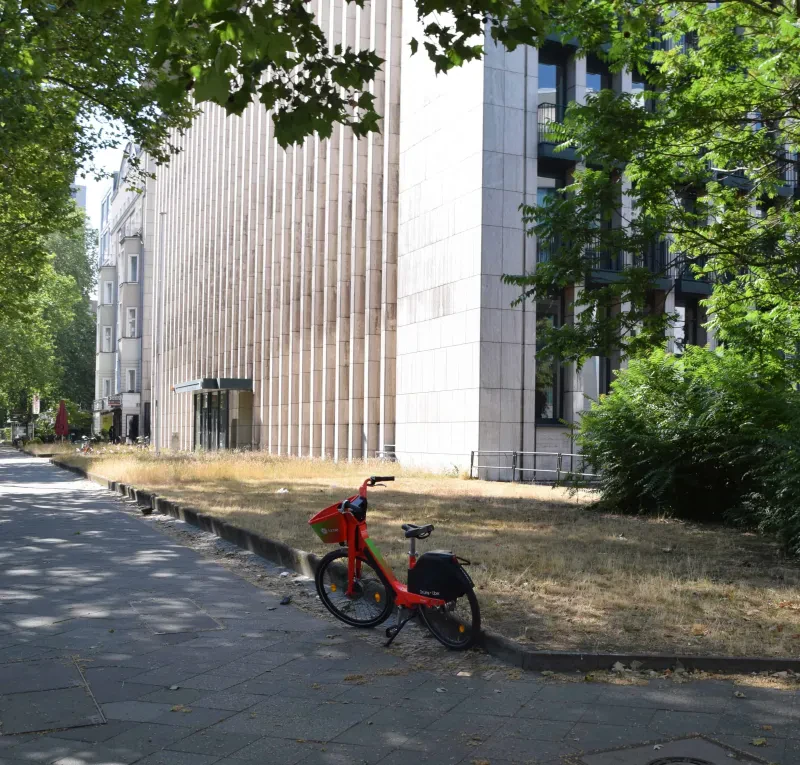 Vor einem Gebäude steht ein Fahrrad, davor ein Stolperstein.