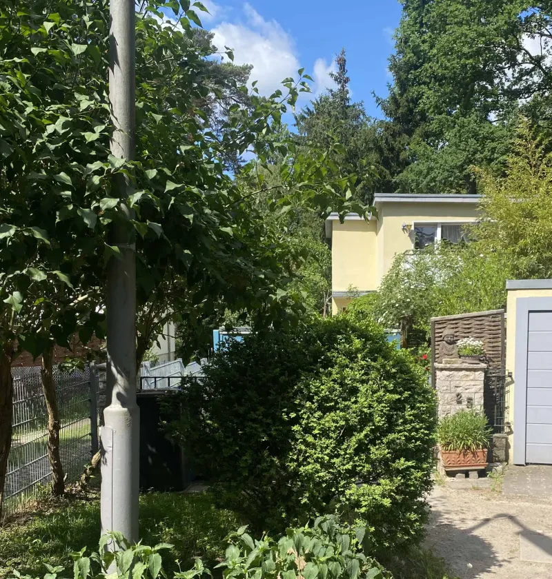 Ein Haus hinter einem Zaun und einer Hecke.
