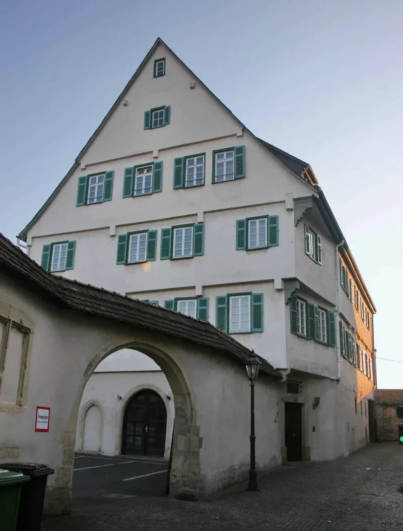 Ein mittelalterliches Gebäude, davor eine Toreinfahrt in einen Innenhof.