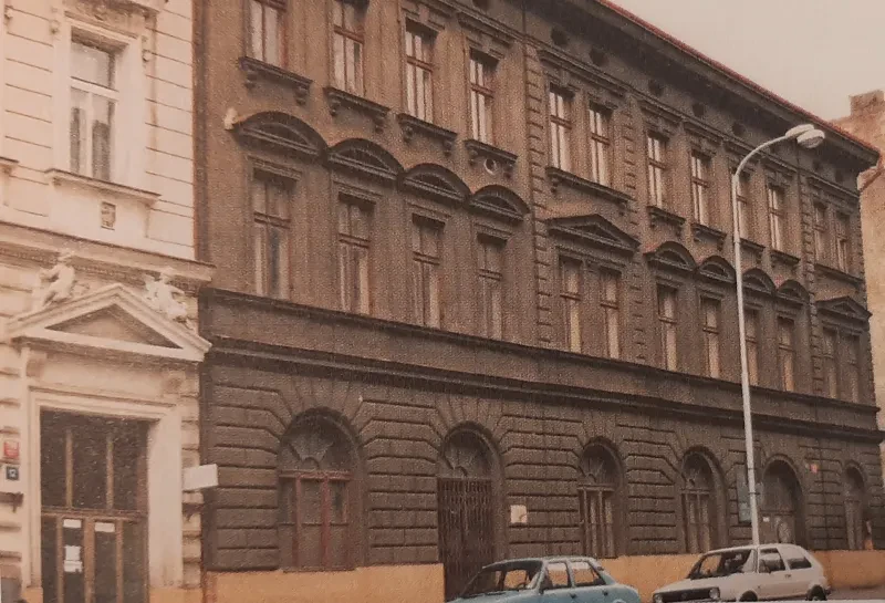 Ein dreistöckiges, goßes, dunkles Steinhaus mit Bogenfenstern im Erdgeschoß.