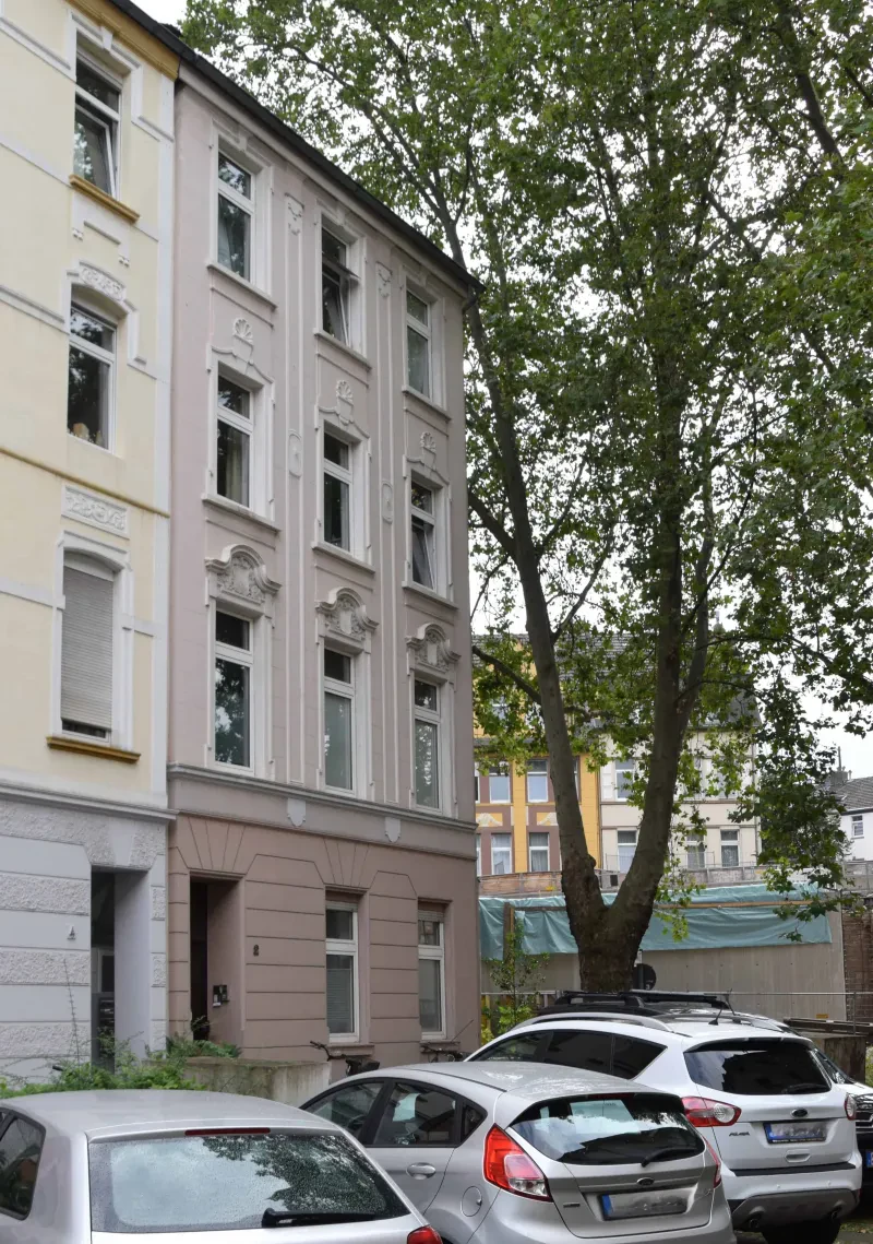 Ein Wohnhaus mit drei PKW davor.