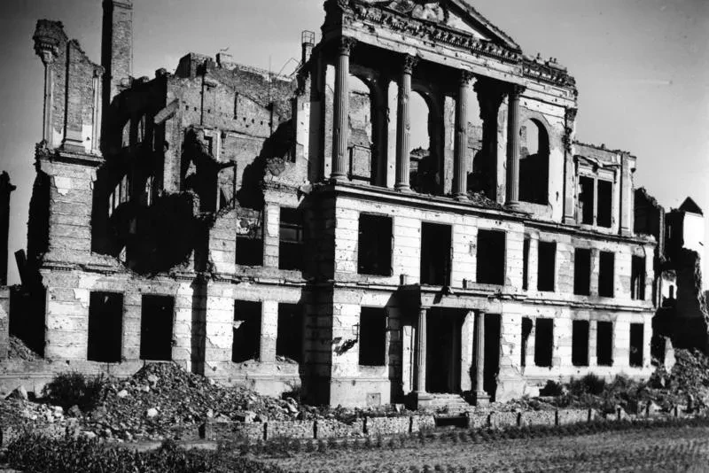 Ruine eines dreistöckigen Gebäudes mit Säulenresten und Spitzgiebel in der obersten Etage.