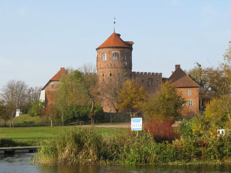 Blick über einen Teich auf die Burg mit dem Burgturm im Vordergrund.