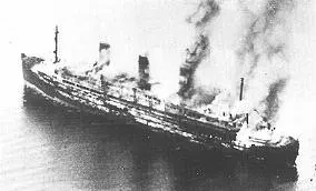 Ein brennendes Schiff, schwarz-weiß Foto, aus der Luft fotografiert.