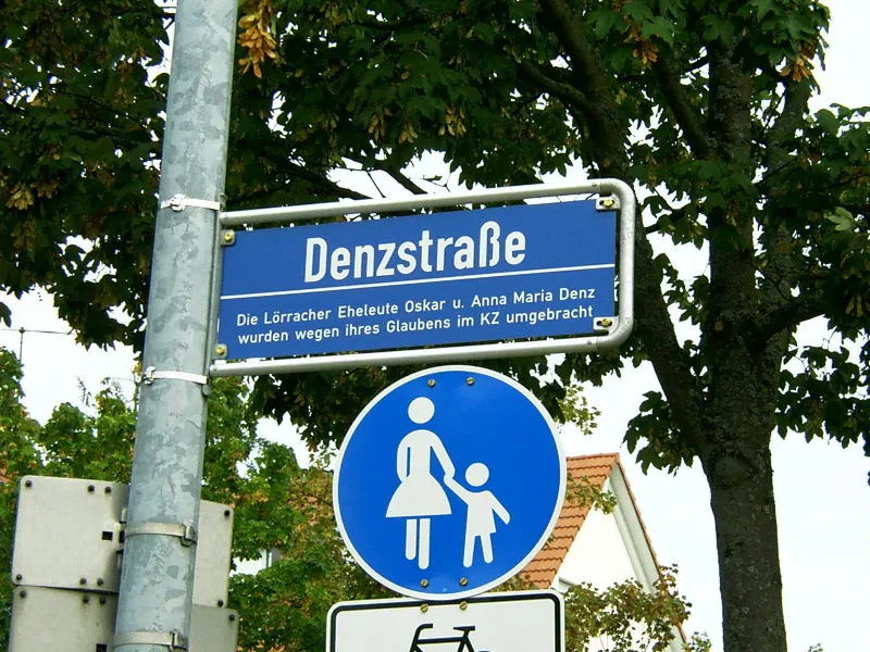 Ein Straßenschild mit der Aufschrift: "Denzstraße - Die Lörracher Eheleute Oskar u. Anna Maria Denz wurden wegen ihres Glaubens im KZ umgebracht"