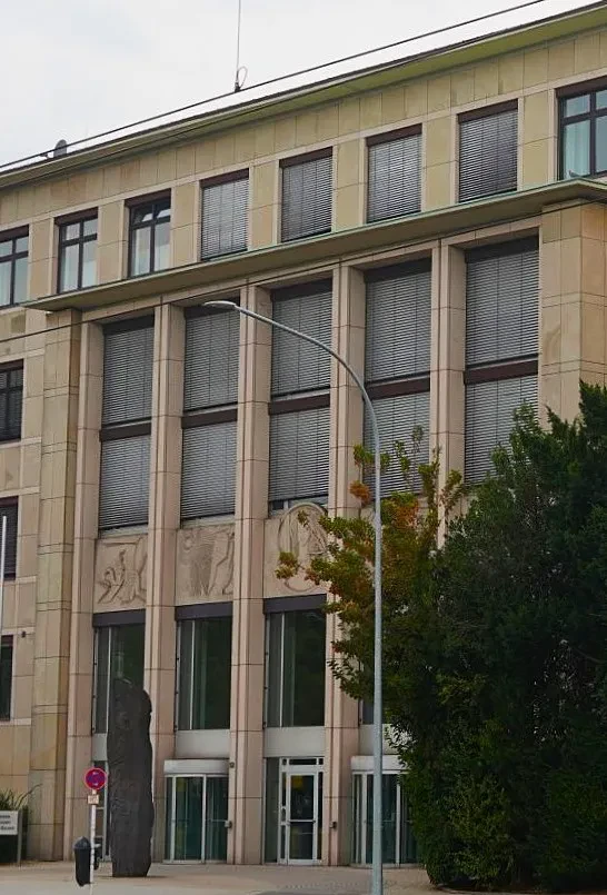 Ein hervortretender Gebäudeteil mit Aluminiumtüren und verkleiderter heller Steinfassade.
