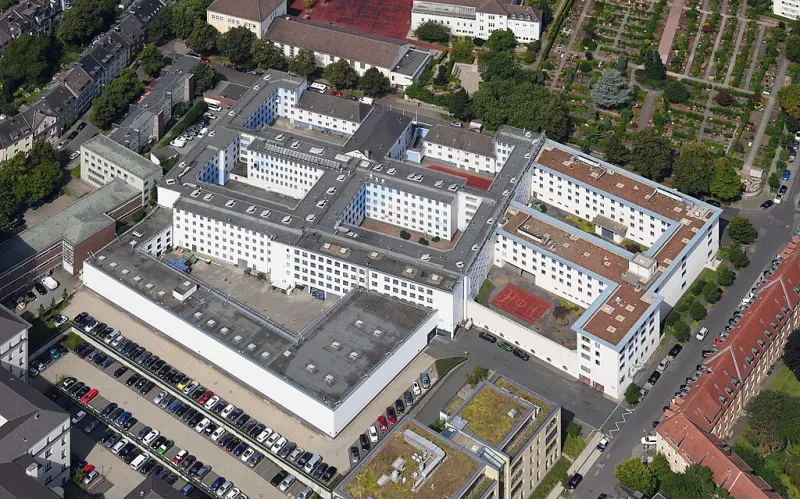 Luftaufnahme von weiß verputzten fünfstöckigen Gebäuden, die sieben Innenhöfe umgeben.