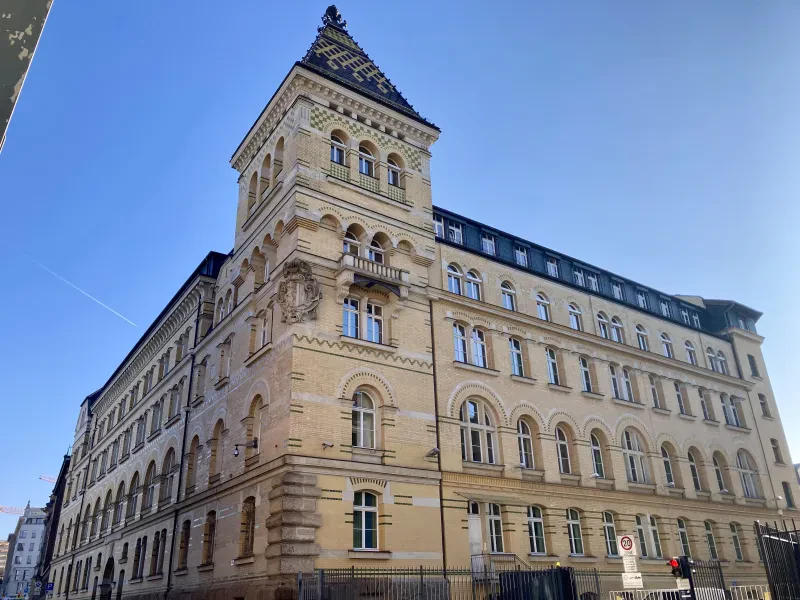 Ein historischer Ziegel- und Steinbau mit einem markanten Turm ist zu sehen.