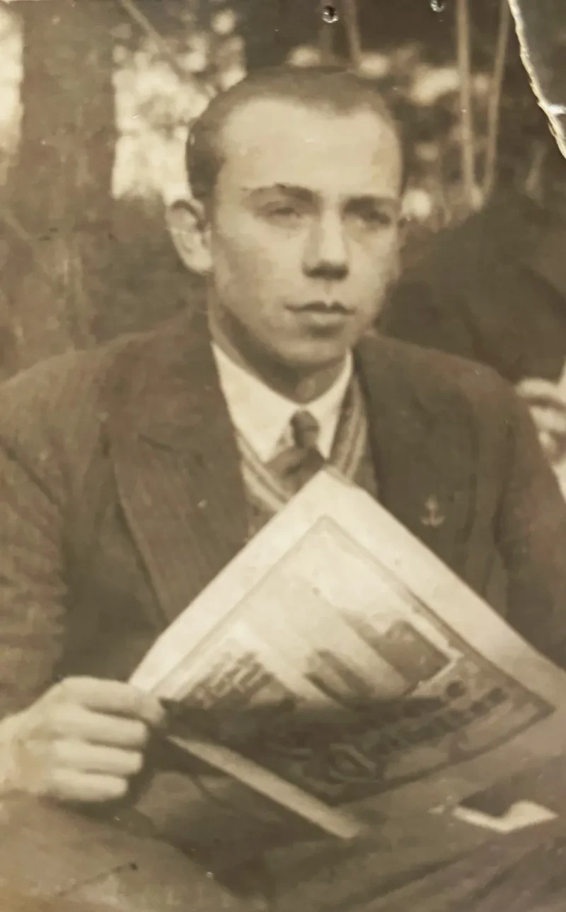 Ein junger Mann mit Anzug und Krawatte hält eine Zeitschrift in der Hand.