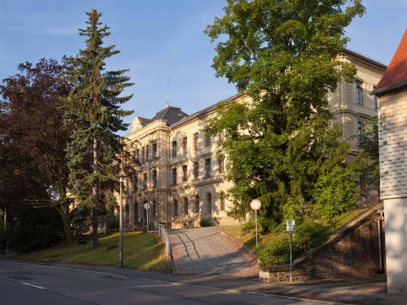 Justizgebäude in Freiberg, ein Weg führt durch Bäume zum Eingang.