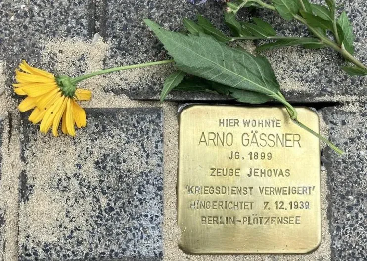 Ein Stolperstein, darüber liegt eine Blume.