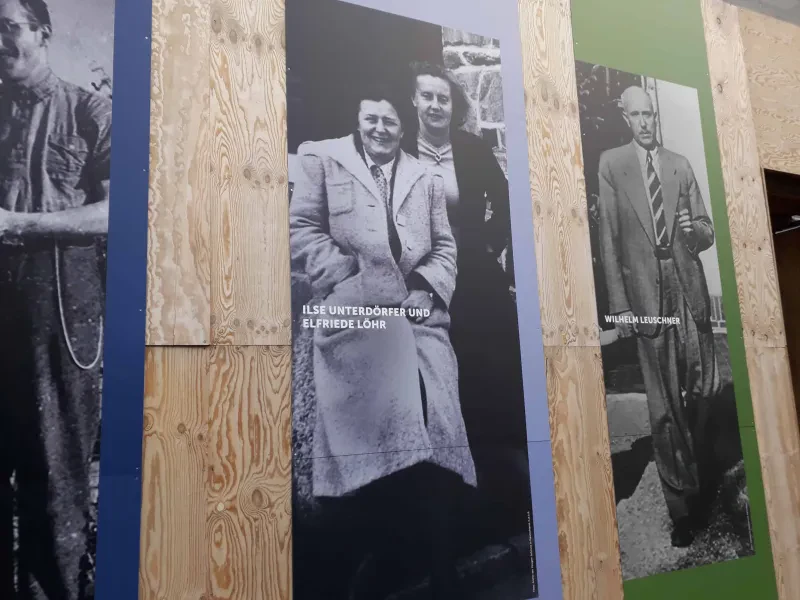 Zwei Frauen auf einem Plakat, das auf einer Holzwand befestigt ist.