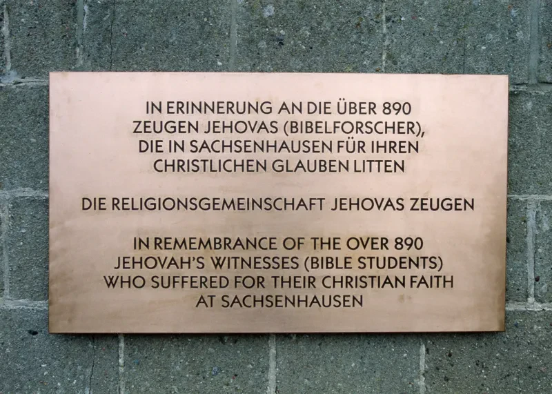 Gedenktafel mit der Aufschrift "In Erinnerung an die über 890 Zeugen Jehovas (Bibelforscher), die in Sachsenhausen für ihren christlichen Glauben litten - Die Religionsgemeinschaft Jehovas Zeugen" sowie einer englischen Übersetzung, 1999.