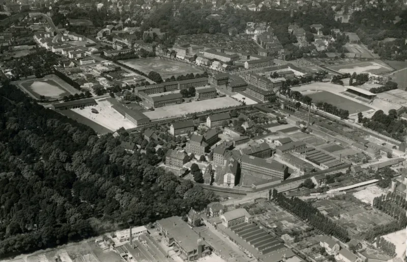 Historische Luftaufnahme des Gefängnisses an der Castroper Straße in Bochum aus den 1950er Jahren; Gebäudekomplex mit mehreren Trakten und Innenhöfen, umgeben von Straßen und Wohnbebauung.