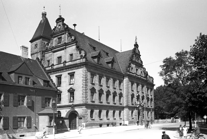 Ein großes Steinhaus, mehrere Personen laufen davor.