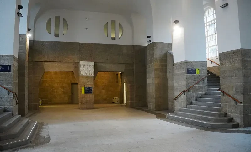 Zwei Freitreppen gehen von einem hohen überdachten Innenhof ab, dessen Wände aus gehauenen Natursteinen bestehen.