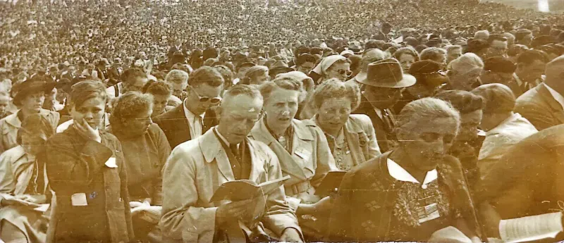 Eine Menschenmenge singt bei einem Kongress. Die Leute schauen in die Liederbücher.