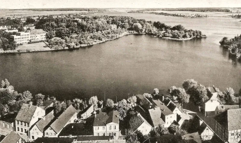 Blick auf einen See, eine Häuserreihe im Vordergrund.
