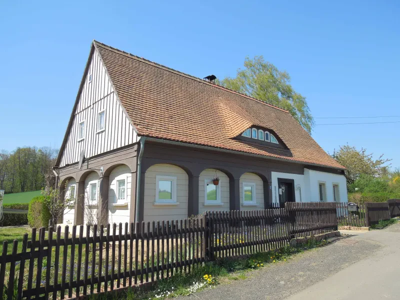 Ein Oberlausitzer Umgebindehaus hinter einem Gartenzaun.