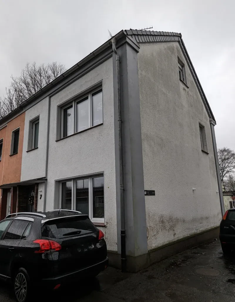 Ein weißes Reihenhaus, davor ein Auto.