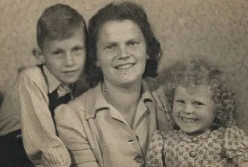 Ein ca. 8jähriger Junge und ein ca 3jähriges Mädchen schmiegen sich lächelnd an ihre Mutter.
