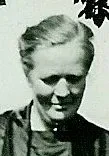 Schwarzweißbild einer Frau die draußen in die Kamera lächelt.