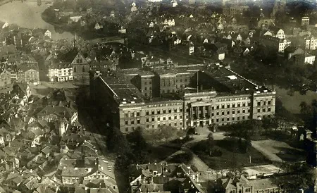 Diese Aufnahme zeigt das alte Regierungsgebäude in Kassel, Schloßplatz 8, an dessen Stelle heute das Regierungspräsidium steht. In der linken Bildhälfte ist - in der Verlängerung der Brücke über die Fulda nach unten- die Brüderkirche zu sehen. Sitz der Sondergerichtsbarkeit.