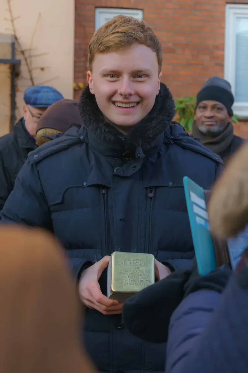 Ein Jugendlicher hält einen Stolperstein in der Hand.