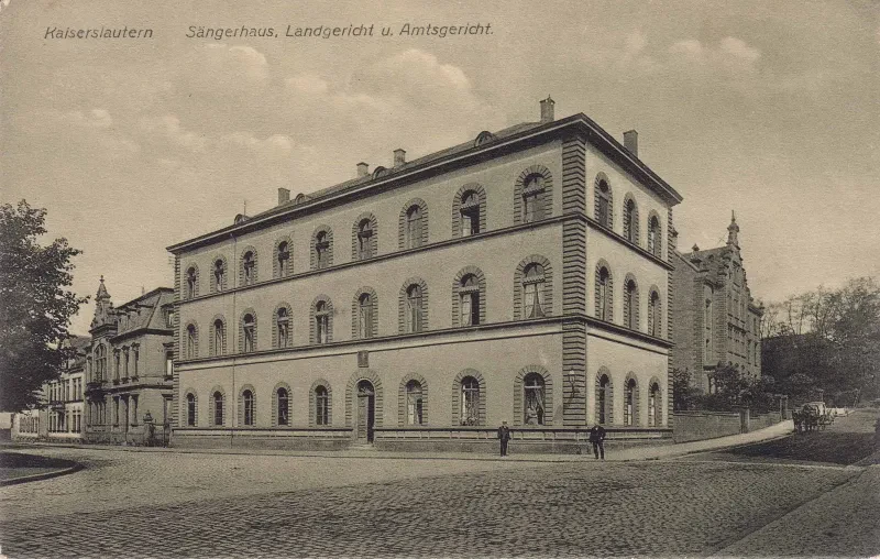 Alte Postkarte zeigt ein großes Gebäude, davor zwei Männer. Aufschrift auf der Postkarte: "Kaiserslautern Sängerhaus, Landgericht u. Amtsgericht"