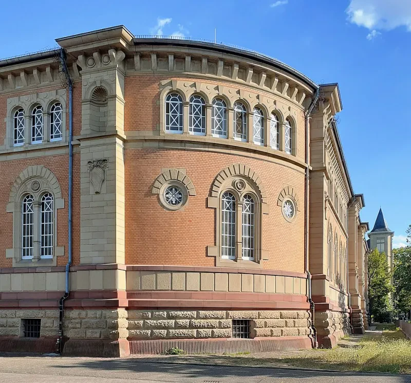 Ein langgestrecktes, dreistöckiges Gebäude in Pastellfarben mit abgerundeten Gebäudeecken.