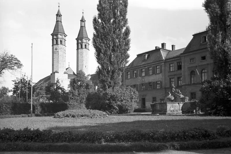 Großer Gebäudekomplex mit zwei hohen runden Türmen in einem Park.
