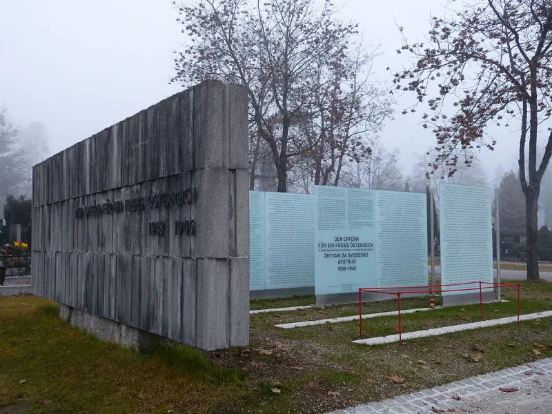 Links ein grauer Betonblock mit der Aufschrift „Den Opfern für ein freies Österreich 1938-1945“, rechts mehrere Tafeln mit Namen.