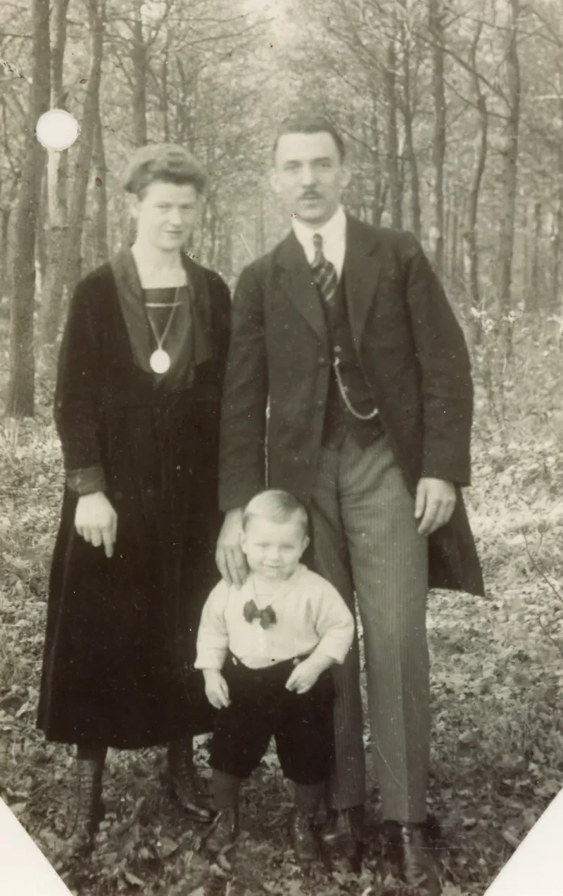 Eine Familie (Mutter, Vater, Kind) vor einem Wald. Das Foto in einem Studio aufgenommen.