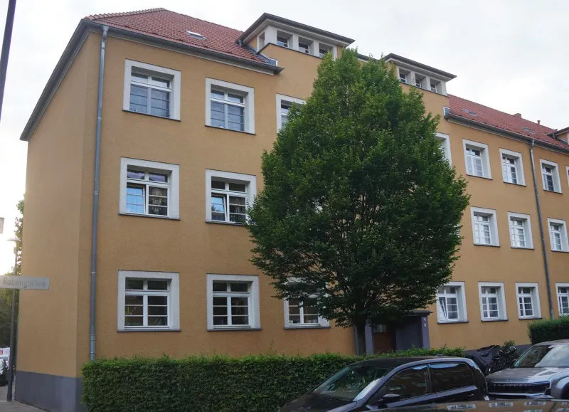 Ein dreistöckiges gelb verputztes Wohnhaus mit ausgebautem Satteldach.