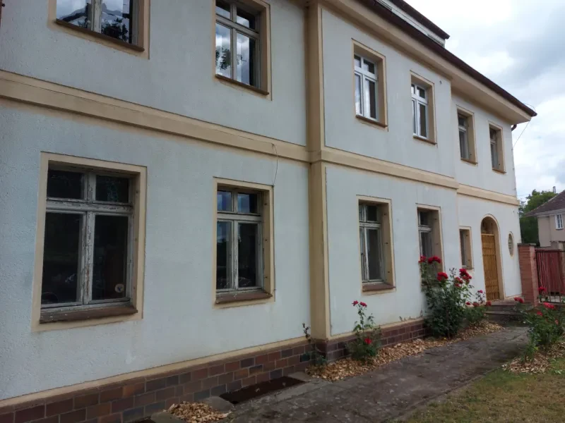 Ein leerstehendes villenähnliches Gebäude, davor blühen Rosen.
