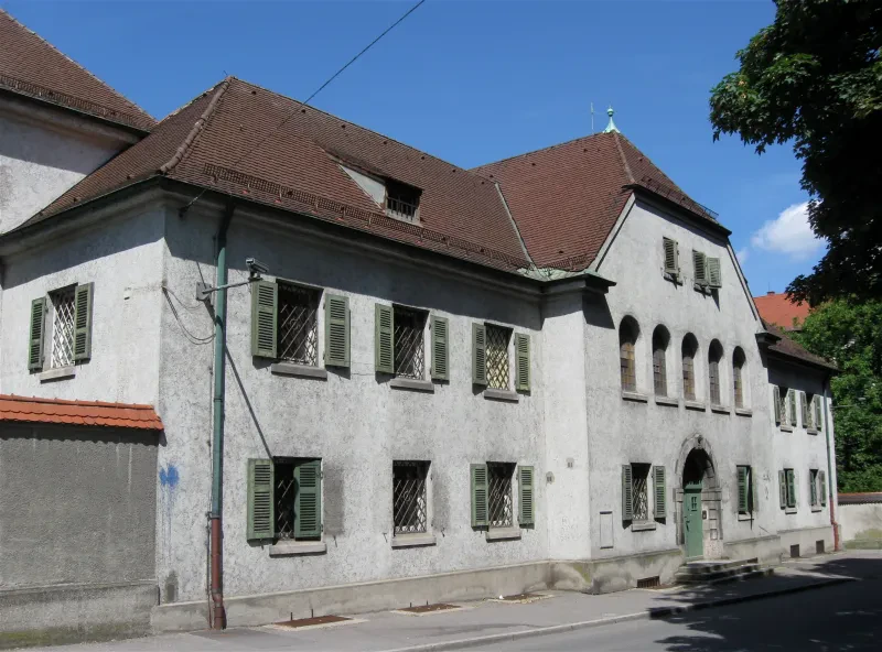 Blick auf ein weißes Gebäude mit vergitterten Fenstern.
