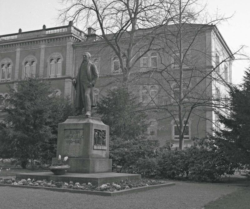 Vor einem dreistöckigem Schulgebäude befindet sich die Statue des Schriftstellers Johann Peter Hebel.