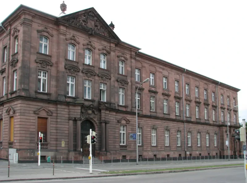 Ein dreistöckiges rotes Gebäude hinter einer Verkehrsstraße.