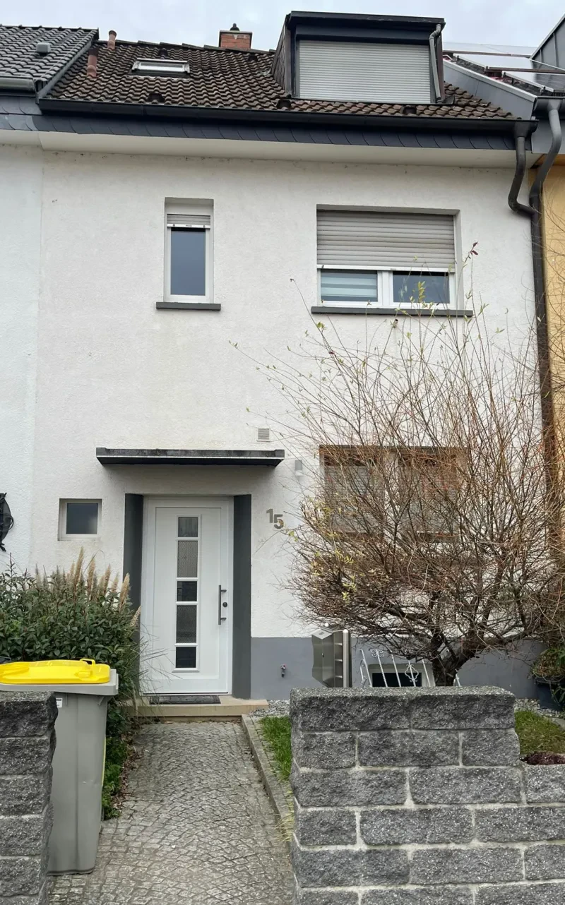 Ein schmales, weiß verputztes Haus mit Satteldach hat zwei Stockwerke.