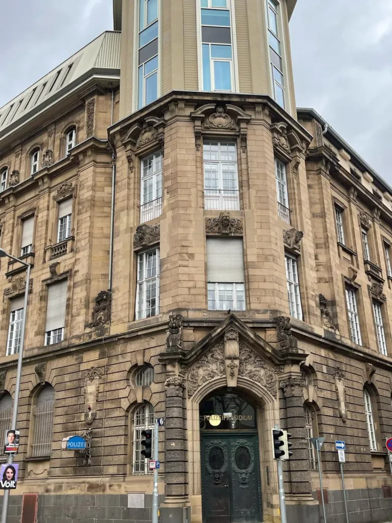 Ein fünfstöckiges Eckgebäude, wobei die oberste Etage neu aufgesetzt wurde.