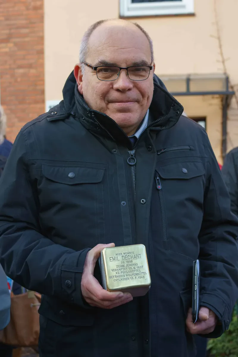 Ein Mann hält einen Stolperstein in der Hand.