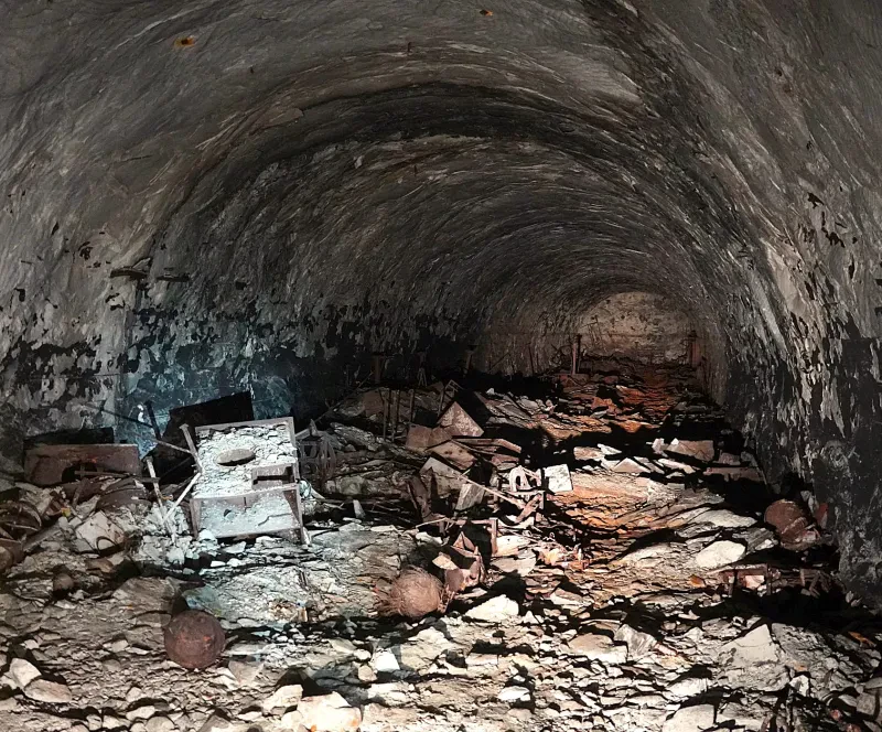 Teile von Rohren, Zwischendecken und Ausrüstung liegen zerstört und verstreut auf dem Boden eines Stollens.