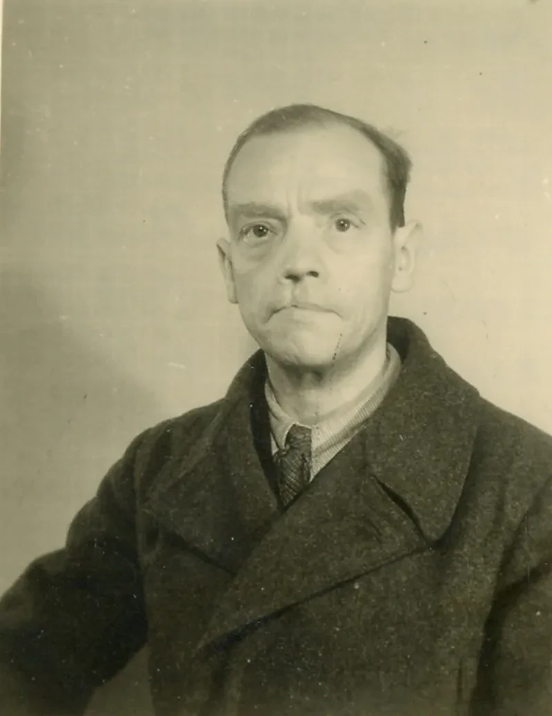 Ein Mann in den 40er Jahren mit Krawatte und dunklem Anzug, sichtbar gezeichnet von der KZ-Haft. An seiner Oberlippe hat er eine Unfallnarbe.