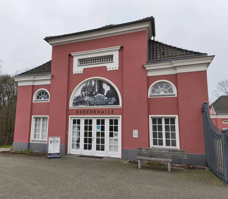 Ein rot gestrichenes Gebäude, Über dem Portal die Inschrift: Gedenkhalle
